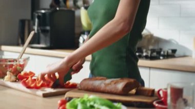 Mutfak tezgahında kırmızı biber doğrayan kız kablosuz kulaklıkla müzik dinliyor. Neşeli kadın kulaklıkla sebze salatası hazırlıyor. Öğle yemeği için vitamin malzemeleri dilimleyen kadın..