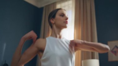 Enerjik sporcu kollarını hareket ettiriyor, evde yoga egzersizi yapıyor. Oturma odasındaki paspasın üzerinde spor yapan odaklanmış bir kadın. Fit genç bayan sabahları dinamik spor antrenmanında sağlıklı vücudu esnetiyor..