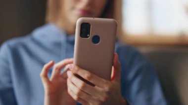 Kadın elleri kapalı çekimde cep telefonunu kaydırıyor. Akıllı telefondan ev koltuğu almayı seçen duygusal genç bayan. Gülümseyen kız cep telefonu ekranını dinliyor ve içeride online sipariş veriyor..