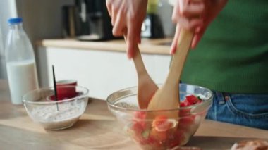 Modern mutfakta kaşıklarla taze salata karıştıran, akıllı telefonlardan konuşan bir kadın. Sağlıklı kahvaltı için sebze hazırlayan rahat bir kız arıyor. Mutfakta aşçılık yapan mutlu kadın..