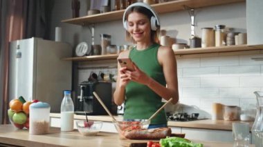 Mutfakta akıllı telefon kullanan bir kadın yemek yaparken mesaj okuyor. Kulaklıklı neşeli bir kadın cep telefonunda müzik dinletiyor. Kulaklıklı gülümseyen kız kahvaltıda cep telefonuyla eğleniyor..