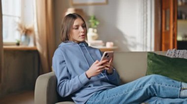 Cep telefonu mesajları okuyan bir bayan rahat bir dairede dinleniyor. Ciddi bir kadın akıllı telefon uygulamasına göz atıyor. Rahatlamış kız rahatsız edici cep telefonu mesajı alıyor.