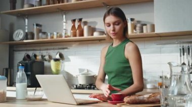 Kahvaltı yapan kız mutfaktaki dizüstü bilgisayarda çalışıyor. Yeşil gömlekli rahat bir kadın bilgisayar klavyesinde sabahları espresso içiyor. Ciddi kadın bağımsız merkez ofiste proje yaratıyor..