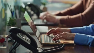 İş arkadaşları ofis çalışma alanında dizüstü bilgisayarı elden ele gezdiriyorlar. Masalarda çalışan profesyonel yöneticiler görevleri tartışıyor. İş adamları modern kurumsal çevrede proje üzerinde işbirliği yapıyorlar.