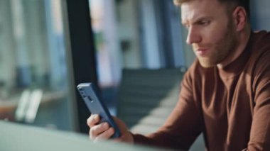 Ofisin içinde akıllı telefonlara bakan düşünceli bir adam. İş yerinde masa başında cep telefonu kullanan odaklanmış bir işadamı. Ciddi profesyonel yönetici cep telefonu okuma e- postalarını kontrol ediyor.