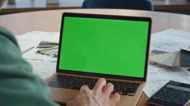 Mimari şirketinin ofis masasında krom dizüstü bilgisayarda sörf yapan yaratıcı yönetici. Yeşil ekran dokunmatik ekran kullanan bilinmeyen bir adam. İş adamı iş yerinde çevrimiçi modelleme aygıtına göz atıyor.