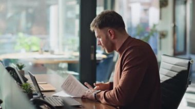 Modern ofis çalışma alanındaki kağıtları inceleyen zeki bir iş adamı. Bilgisayar masasında çalışan şaşkın şirket yöneticisi. Verimlilikle evrak işleriyle uğraşan ciddi bir adam..