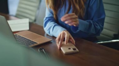 Ofiste laptopta çalışan profesyonel bir kadın cep telefonu alıyor. İş yerinde rahatsız edici akıllı telefon tebligatı okumaktan bıkmış bir çalışan. İş kadını telefon aramaktan hayal kırıklığına uğradı.