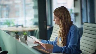 Ofis masasında belgeleri okuyan başarılı bir kadın. Modern çalışma alanında evrak işleriyle uğraşan profesyonel bir yönetici. Güvenilir iş kadını, şirket odasındaki iş raporlarını incelemekten memnun..