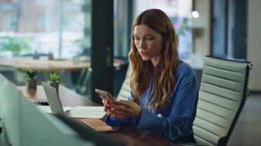 Ofis çalışanı ofisteki iş yerindeki mesajla tatmin olmamış cep telefonunu kapatıyor. Masada bilgisayarla akıllı telefon banka bildirimi okuyan hoşnutsuz bir iş kadını. Sinirli yönetici görünümlü telefon.