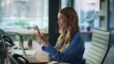 Ofis çalışanı cep telefonunun sosyal medya içeriğini araştırıyor. Gülümseyen iş kadını modern iş yerinde cep telefonu iletişiminden hoşlanır. Esmer mesajlaşma akıllı telefon.