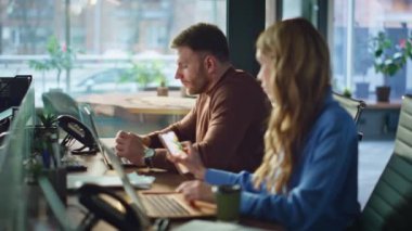 Modern ofis iç çekimlerinde birlikte çalışan aşırı yüklenmiş çalışanlar. Çalışma masasında esneyen iş adamıyla iş birliği yapan bir iş kadını. İki yönetici iş yerinde dizüstü bilgisayar yazmaktan yoruldu.