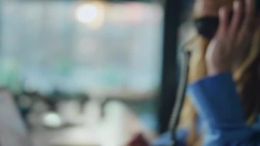 Ofiste telefonla konuşan gülümseyen bir danışman. Yakın plan. Pozitif kadın, telefon danışmanına uzaktan cevap veriyor. Mutlu iş kadını modern iş yerinde dostça sohbetin keyfini çıkar..