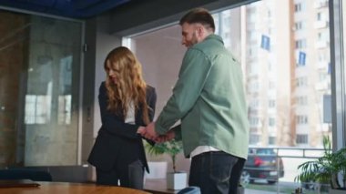 Modern ofisteki adamla tokalaşan neşeli iş kadını. Şirket işyerindeki iş toplantısında kendine güvenen bir kadın iş adayını selamlıyor. Gülümseyen insanlar toplantı odasında otururlar. 