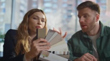 Modern ofis kapanışında renk örnekleri gösteren profesyonel dekoratör danışmanı. İş yerinde bir adamla tasarım projesini tartışan bir kadın. Özenli erkek kumaş örnekleri seçiyor.