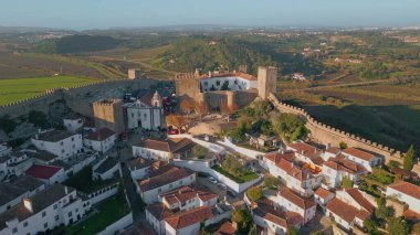 İnsansız hava aracı manzaralı eski taş kale güneşli kırsal bölgeye yerleştirilmiş. Yeşil alanlar ve ortaçağ mimarisi olan manzaralı bir yer. Tarihi binaları ve tarım arazileri olan kırsal bir kasaba. Trip konsepti
