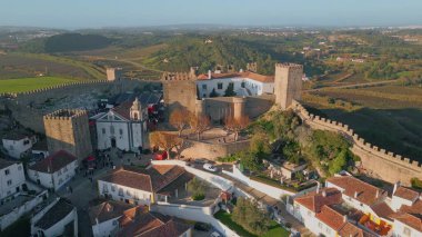 Şehir Obidos Ortaçağ Şatosu 'nu insansız hava aracı görüşünden yüksek taş duvarlarla donatmıştı. Eski bina peyzaj ile kusursuz bir şekilde harmanlanıyor. Tarihi mimarinin zamansız güzelliğini gösteren antik bir yapı.