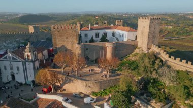 Taş duvarlar ve insansız hava aracı manzaralı güzel bir ortaçağ kale avlusu. Kırsal kesimde yeşil kırsal kesimde güneşli bir gün yaşanıyor. Çevresi yeşilliklerle çevrili antik Obidos tahkimatı