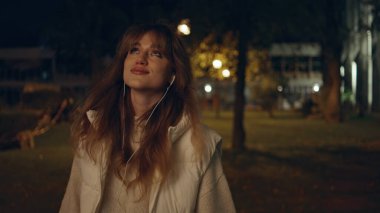 Geceleri müzik dinleyen mutlu bir bayan yakına bakıyor. Karanlık şehirde kulaklıklarla dolaşan kaygısız bir kadın turist. Rahat kız, sokak lambalarıyla aydınlatılmış kasabada geç saatlere kadar gezinti yapıyor..