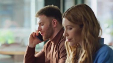 Profesyonel bir adam, ofis masasında oturan akıllı telefondan kadın iş arkadaşıyla konuşuyor. Ciddi bir iş adamı iş yerinde bayan meslektaşıyla telefon görüşmesi yapıyor. Şirket ekibi görevlere odaklandı