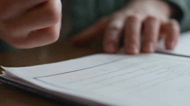 İş adamı yakın planda anlaşma imzalıyor. Bilinmeyen yönetmenin ofiste iş belgesine imza atması. Erkek CEO, masa başı işyerindeki resmi kağıt formlarını doldurmak için anlaşma yapıyor..