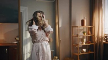 Neşeli bayan aynanın yansımasına bakıyor. Yeni bir gün, sıcak yatak odasında zum yapıyor. İpek bornozlu, heyecanlı bir kadın. Sabahın keyfini çıkarıyor. Neşeli bayan lüks dairede tek başına eğleniyor.