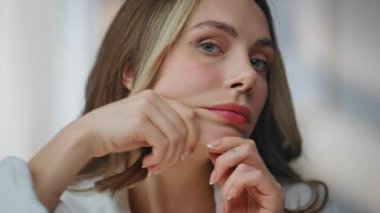 Genç bir kadın banyoda yüz ve çene masajı yapıyor. Resimli gülümseyen kadın rahat evdeki güzellik kamerasından zevk alıyor. Mutlu manken yanaklarına dokunuyor.