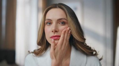 Endişeli genç kadın göz çevresindeki kırışıklıkları inceliyor. Mutlu olmayan milenyum hanımı, kamera portresine bakan cilt hastalığından memnun değil. Kozmetik bilimcilerin yakın plan buluşması. 