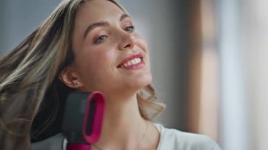 Mutlu ev hanımı elinde kurutucuyla banyoda saçına dokunuyor. Tatmin olmuş, aynaya bakan, ipeksi Chevelure 'u evde kurutan bir kız. Güzel bir kadın sabahları güzellik rutininden zevk alıyor. Kişisel bakım ve refah. 