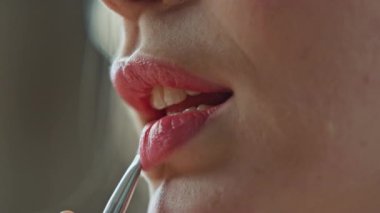 Yakın çekim modeli evde ruj sürüyor. Pembe renkli merhem süren tımar edilmiş bir kadın içeride eğleniyor. Dairede gül nemlendirici dudak bakımı kullanarak yüz makyajı yapan isimsiz, rahat bir kadın. 