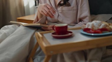 Kahvaltılık kadın elleri yatakta roman okuyor. Sayfaları çeviren tanınmamış bir kadın evde tembelce hafta sonunun keyfini çıkarıyor. Gülümseyen manken, yatak odasında yemek yiyor, elinde kitap tutuyor, espresso bardağını içeri götürüyor.