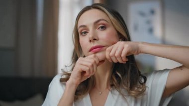 Genç bir kadın banyoda yüz ve çene masajı taklidi yapıyor. Portre gülümseyen bayan güzellik rutininden zevk alıyor. Evde kameraya bakıyor. Mutlu manken apartman dairesinde yanaklara dokunuyor.