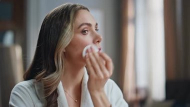 Sakin bayan banyoda temizlikçi. Yakın plan. Kendine güveni tam bir kadın, elinde pamuk tutarak modern dairede sabah rutini yapıyor. Beyaz bornozlu güzel bayan tek başına dikilip, rahat evine aynaya bakıyor. 