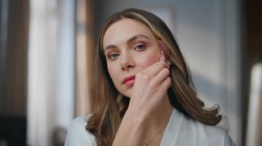 Otel Pov View 'da güzellik aletleri kullanan bir bayan. Cilt bakımı için yeşim taşı tutan gülümseyen kadın yatak odasında yüz bakımı yapıyor. Doğal masaj portresi olan sakin bir kız. Masaj konsepti 