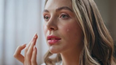 Yakından tatmin olmuş, şımarık yanaklı bir kadın banyoda güzellik rutininin tadını çıkarıyor. Dairesinde nemlendirici krem kullanan sakin, bakımlı bir kadın. Profesyonel bakım ürünü kozmetik konsepti 