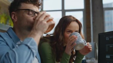 Dolap masasında çay yudumlayan odaklanmış iş arkadaşları. Ofis ekibi birlikte çalışarak Webinar 'ı açık alanda izleyerek projeyi inceliyor. Şirket liderliği takım çalışması kavramı