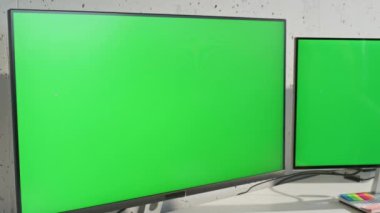 Açık ofis masasında duran iki kroma anahtar görüntüsü uzaklaşır. Dolaptaki bilgisayar faresini kullanarak çalışan yeşil ekran monitörleri. Odaklanmış kadın, iş yerindeki bilgisayarın modelini arıyor.