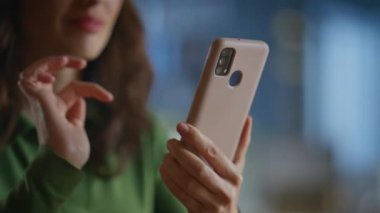 Kadın elleri sabahki ofiste cep telefonunu kaydırıyor. Mutlu rahat iş kadını gülümseyerek sosyal medyada geziniyor şirket işyerinde oturuyor. Şirket yöneticisi bayan cep telefonu ekranını çalıyor. 