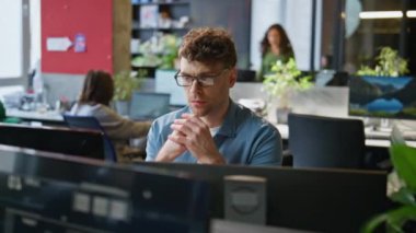 Modern ofis içlerinde karar verme mekanizması çalışan özenli bir adam. Profesyonel yönetici masaüstünde klavye yazma fikri üzerine kafa yoruyor. Açık alanda gözlüklü esmer adam.