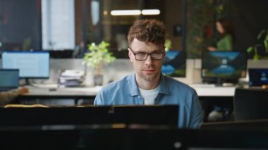 Odaklanmış adam masaüstü açık alanda yakın planda çalışıyor. Gülümseyen serbest çalışan bilgisayar ekranında uzaktan iş meselelerini çözüyor. Çekici genç programcı birlikte çalışmada iş çözümleri düşünüyor 