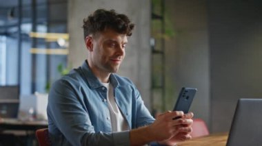 Şirketin CEO 'su internette gezinip cep telefonundan komik mesajlar alıyor. Masada oturmuş akıllı telefon mesajı okuyan mutlu bir işadamı. Pozitif adam iş yerinde eğleniyor. 
