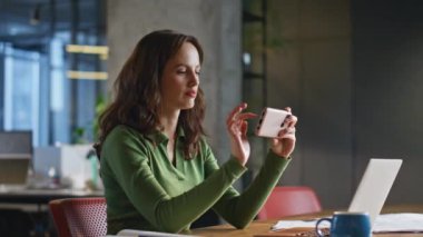 Ofiste cep telefonunu izleyen düşünceli bir kadın. Akıllı telefondan iş e-postalarını okuyan odaklanmış bir iş kadını. Patroniçenin elinde cep telefonu var. Modern odanın içinde Webinar 'ın tadını çıkarıyor.