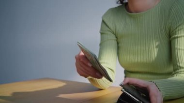 İş kadını, yeni 100 dolarlık Amerikan parasını elinde tutuyor. Amerikan paralarını sayan kadın kasiyer. Zengin bir kadın maaş alıyor, banknotları deri cüzdana koyuyor. Maliye ve ekonomi kavramı 