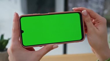 Şirketin iş yerinde el ele tutuşan yatay model cep telefonu. Bilinmeyen kadın uzaktan kumandalı ofisteki yeşil ekran akıllı telefona bakıyor. İş kadını dairede cep telefonuyla konuşuyor.