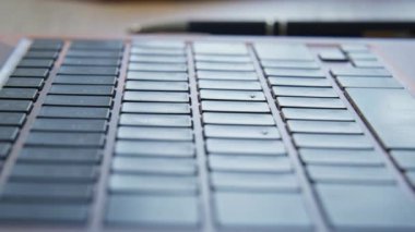 Macro view bilgisayar düğmeleri dairede detaylıdır. Dolly, ahşap ofis masasında kablosuz dijital cihaz çekti. Kapalı mekanda siyah klavyesi olan modern gri dizüstü bilgisayar. Çalışma konsepti teknolojisi
