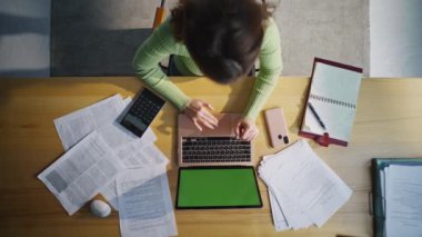 Masa başında yeşil ekran dizüstü bilgisayar yazan kadın. Tanımlanamayan muhasebeci kadın bilgisayarın üst görüntüsünden gelen mesajları analiz ediyor. Ofis çalışanı elleri proje kromakey pc oluşturuluyor