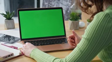 Bilinmeyen kişi çevrimiçi konferansta konuşuyor. Laptop yeşil ekranı kapalı mekanda görüyor. Ofisteki Chroma Key bilgisayarında tanımlanamayan yönetici projesini sunuyor. Model aygıtı kullanan işçiler 