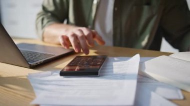 Ofiste hesap makinesiyle el sayımı yapan bir adam var. Profesyonel muhasebeci, iş yerinde dizüstü bilgisayarla çalışırken finansal kayıplar hesaplıyor. Memnun olmayan işadamı endişeli iş krizi