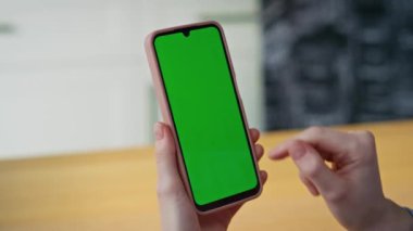 Yakın plan parmaklar dairede yeşil ekran akıllı telefon tarama uygulamasını tıklatıyor. Kimliği belirsiz bir kadın evde online alışveriş için krom anahtarlı cep telefonu kullanıyor. İş yerinde cep telefonu tutan kız elleri..