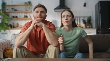 Aile çifti TV 'de spor şampiyonası seyrediyor. Duygusal eşler oturma odasındaki koltukta kazanınca mutlu tepki veriyorlar. Neşeli iki taraftar, apartmanda futbol takımının zaferini kutluyor..